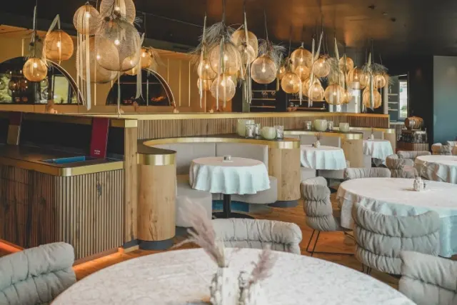 Modernes Restaurant im Hotel Steiner mit stilvollen Hängelampen, runden Tischen und gemütlichen Sitznischen.