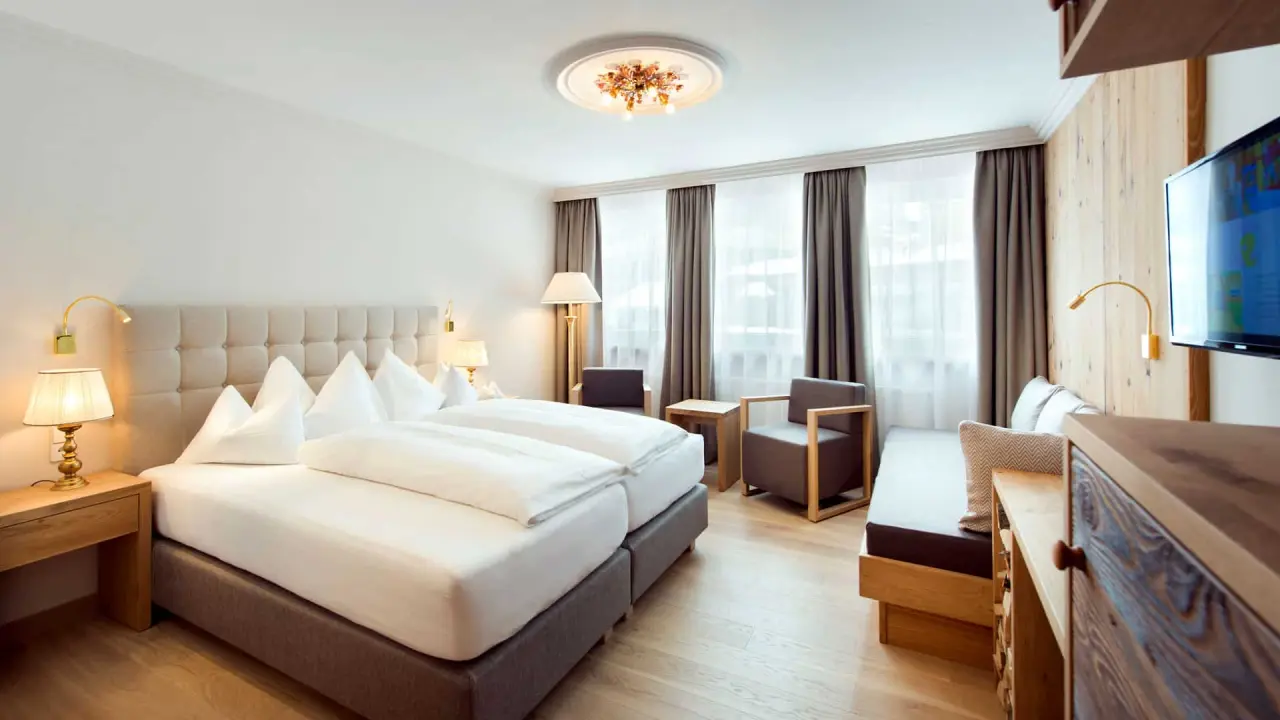 Gemütliches Doppelzimmer im Hotel Steiner mit bequemen Betten, Sitzbereich und modernem Holzdesign.