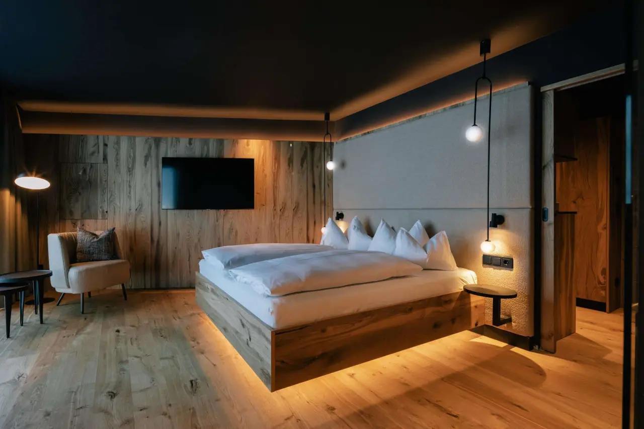 Modernes Doppelzimmer im Hotel Steiner mit Holzelementen, indirekter Beleuchtung und gemütlicher Sitzecke für entspannte Nächte.