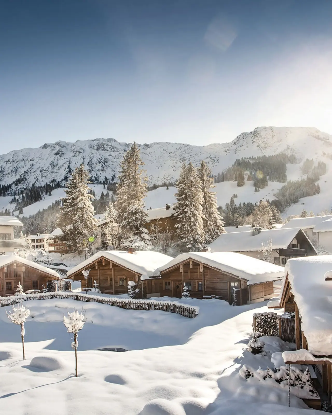 Schneebedeckte Chalets und Tannen vor Bergpanorama im Winter, Parkhotel Jordanbad.