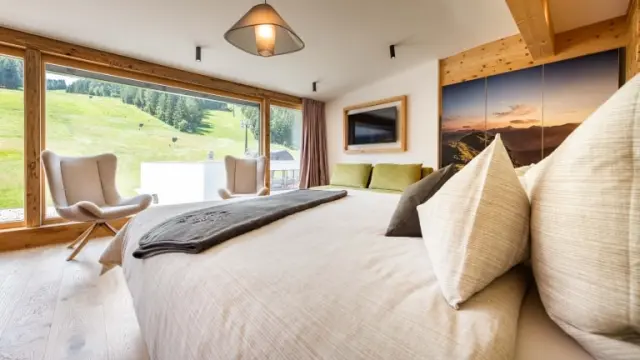 Helles Hotelzimmer im ALMGUT Mountain Wellness Hotel mit Panoramablick auf die Alpen und komfortablem Bett für Entspannung.
