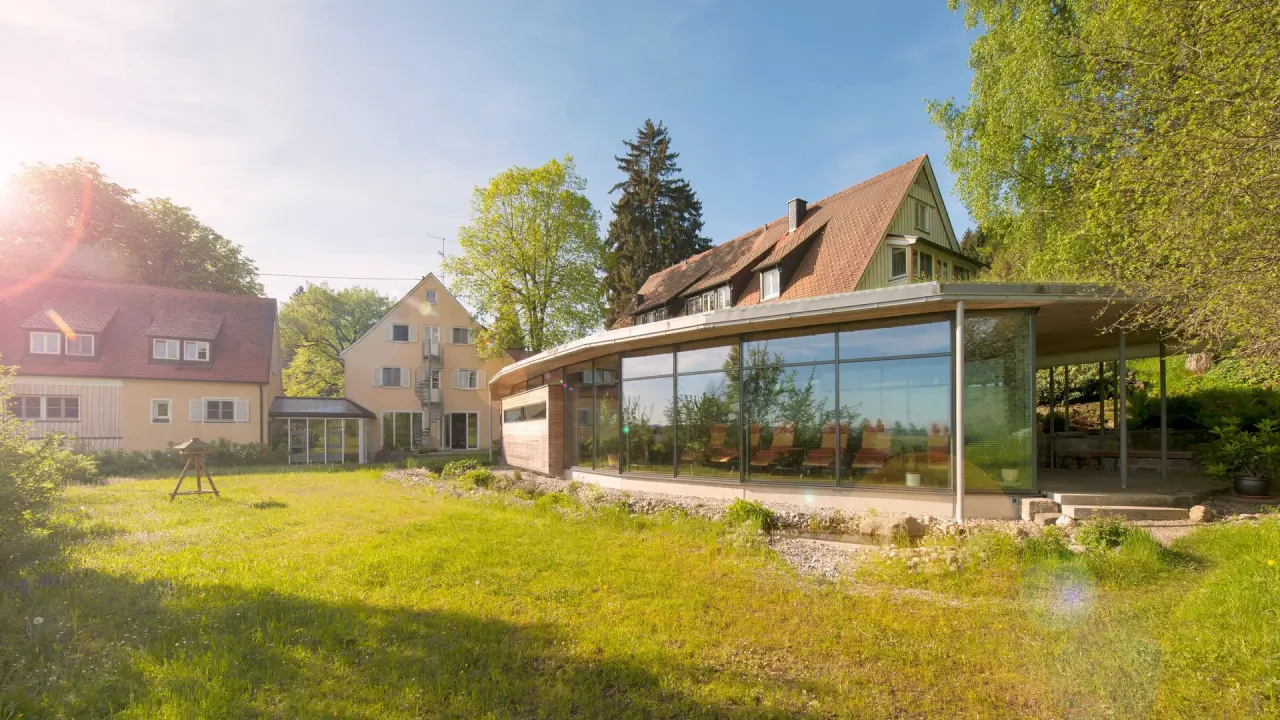 Aussenansicht des Bad Clevers Gesundheitsresort & Spa mit modernem Glasbau und sonnigem Garten.