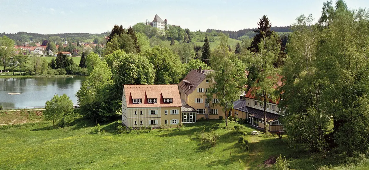 Panoramablick auf Bad Clevers Gesundheitsresort & Spa am See, umgeben von grüner Natur mit Schloss im Hintergrund.