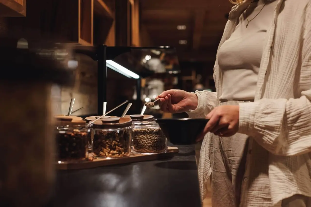 Gast nimmt sich gesunde Müsli-Zutaten vom Buffet im Restaurant des Alpenhotel Kitzbühel am Schwarzsee.