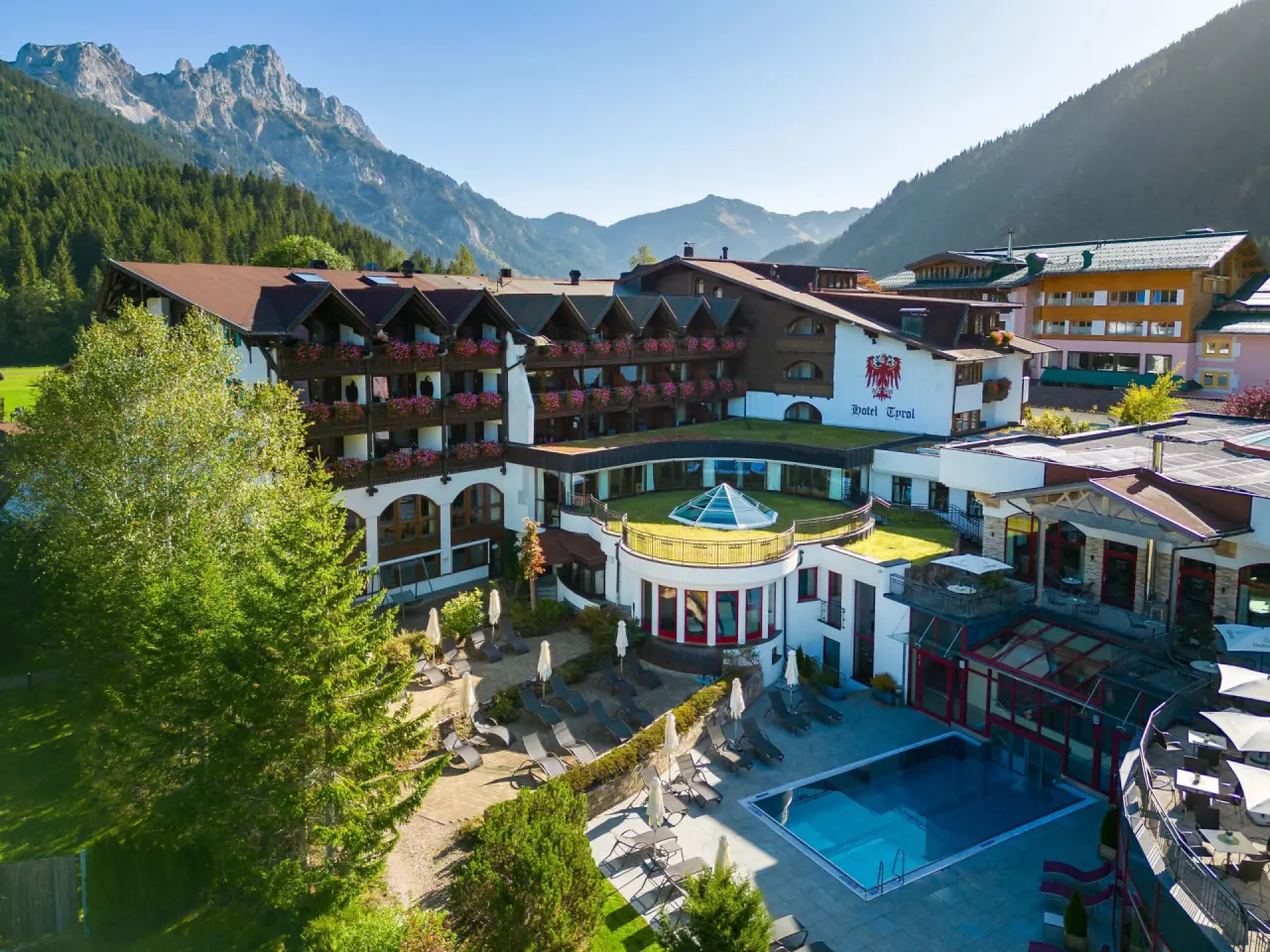 Luftaufnahme des Hotel Tyrol am Haldensee mit Aussenpool, Sonnenterrasse und majestätischem Bergpanorama im Tannheimer Tal.