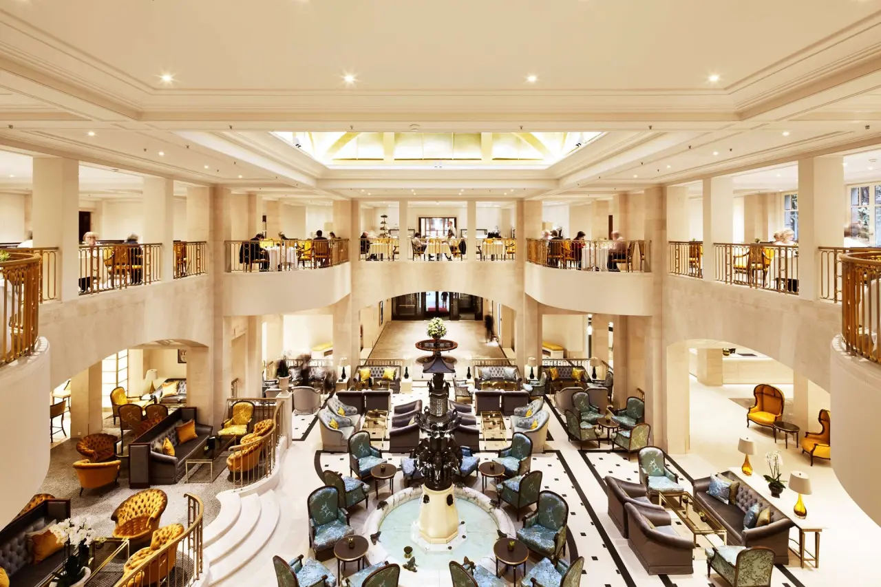Prächtige Lobby des Hotel Adlon Kempinski mit eleganter Einrichtung, Springbrunnen und mehreren Ebenen für Gäste.