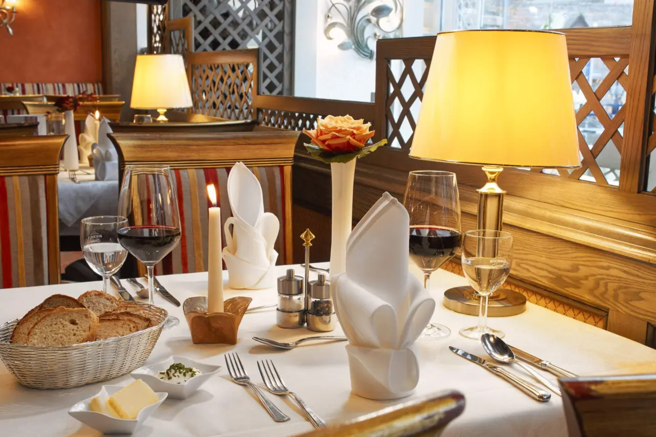 Elegant gedeckter Tisch im Restaurant des Rüters Parkhotel mit Wein, Kerzenlicht und frischem Brot.