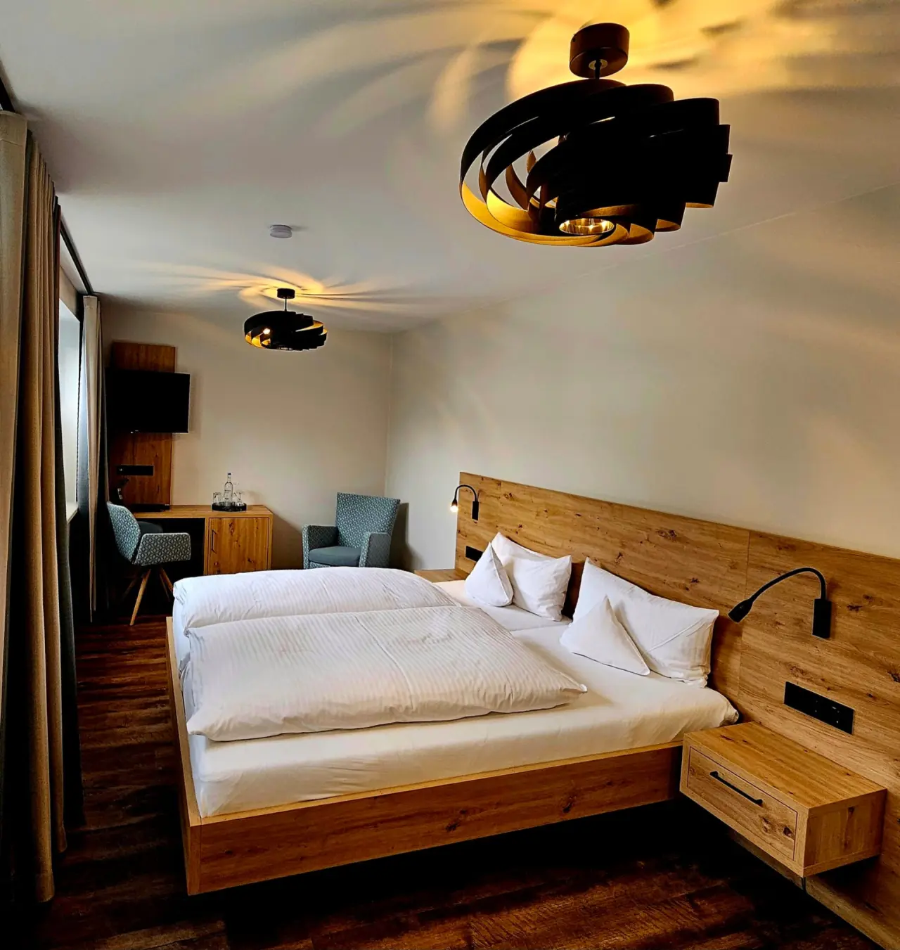 Modernes Doppelzimmer im Rüters Parkhotel mit Holzelementen, bequemen Betten und gemütlicher Beleuchtung.