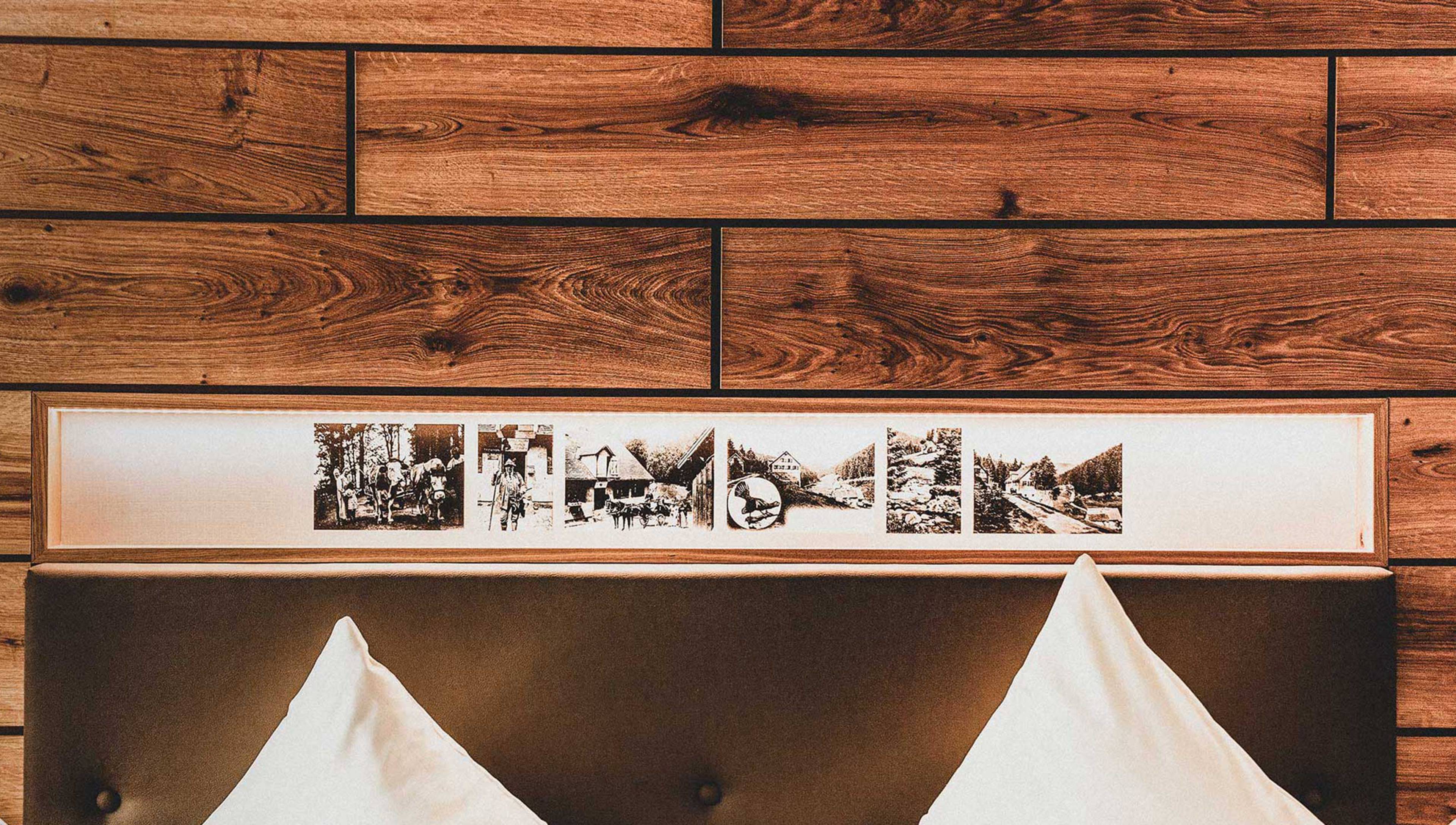 Hotel Forsthaus Auerhahn in Baiersbronn – Detailansicht des Betthaupts mit historischen Bildern im Zimmer | Wellnesshotel Schwarzwald