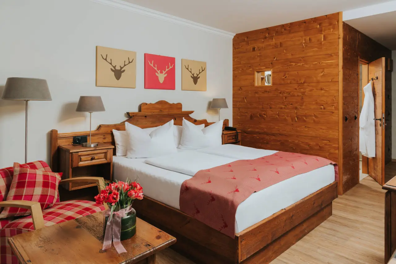 Gemütliches Doppelzimmer im alpinen Stil mit Holzelementen und Hirsch-Dekor im Hotel Drei Quellen Therme.