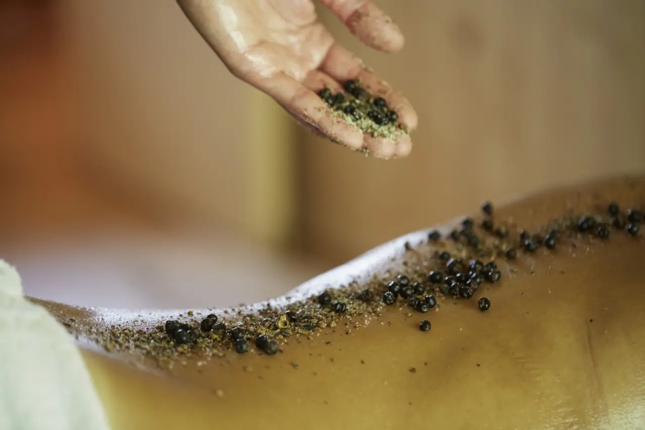 Hand bei der Anwendung eines Körperpeelings im Spa-Bereich des Hubertus Mountain Refugio Allgäu.