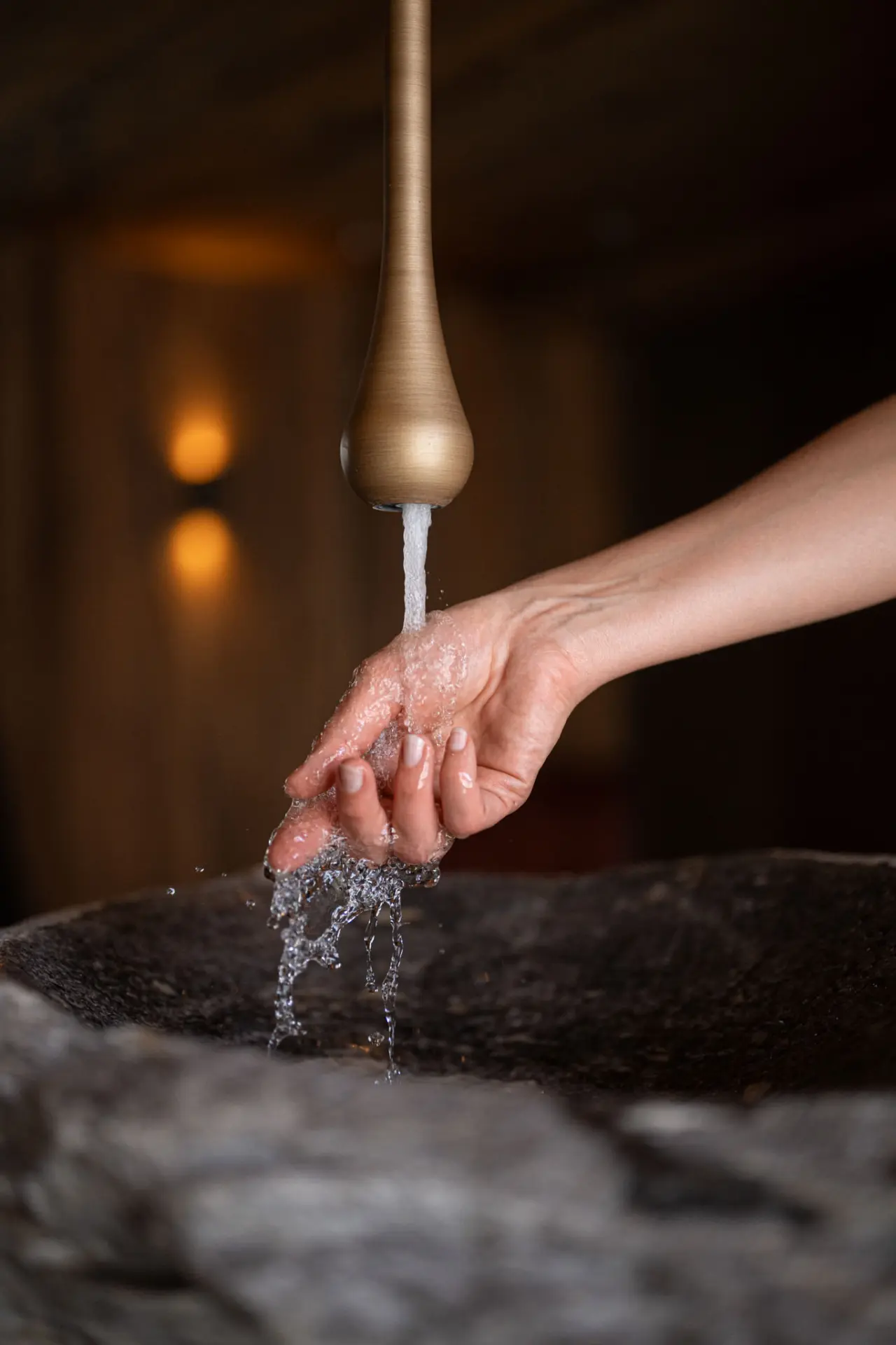 Frisches Wasser aus stilvollem Hahn in Händen eines Gastes im Spa-Bereich des Hotel Johanneshof.