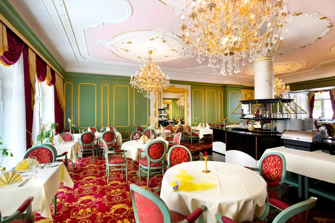 Opulenter Speisesaal mit Kronleuchtern, roten Teppichen und elegant gedeckten Tischen im Häcker´s Fürstenhof Bad Bertrich.