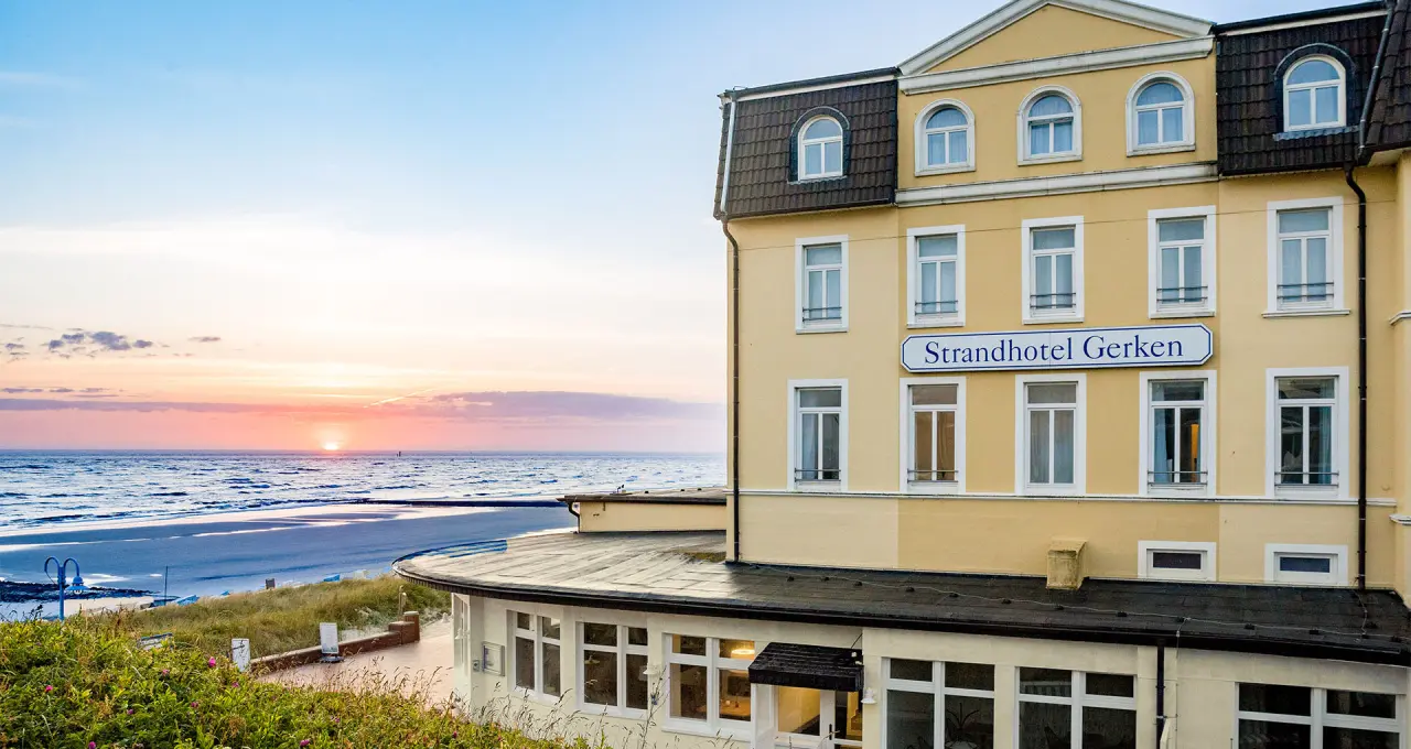 Strandhotel Gerken bei Sonnenuntergang mit Blick auf die Nordsee und den Strand.