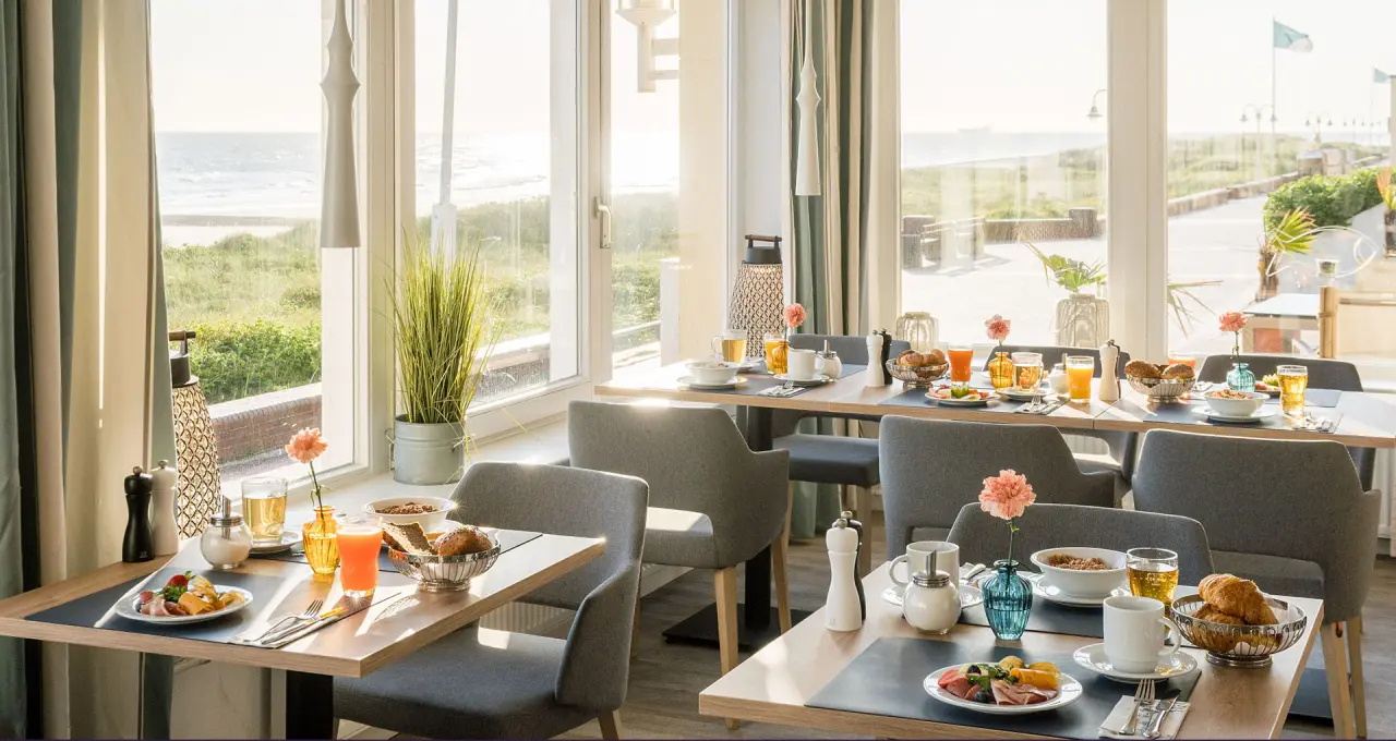Einladendes Frühstücksrestaurant im Strandhotel Gerken mit direktem Blick auf die Nordsee und den Strand.