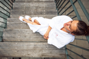Eine entspannte Frau im weißen Bademantel liegt auf einer Holztreppe im Hotel Gotthard Lech.