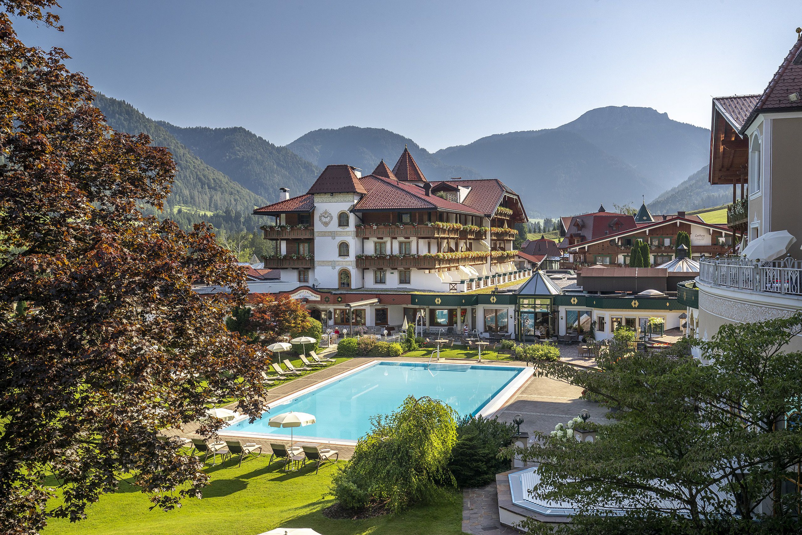 Hotel Der Lärchenhof in Erpfendorf – Hotelansicht mit großem Außenpool und Bergpanorama | Wellnesshotel Tirol