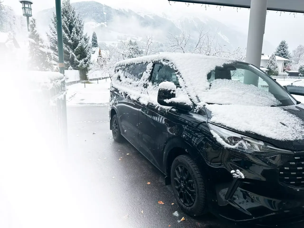 Schneebedecktes Auto vor winterlicher Berglandschaft am Hotel Vitalquelle Montafon
